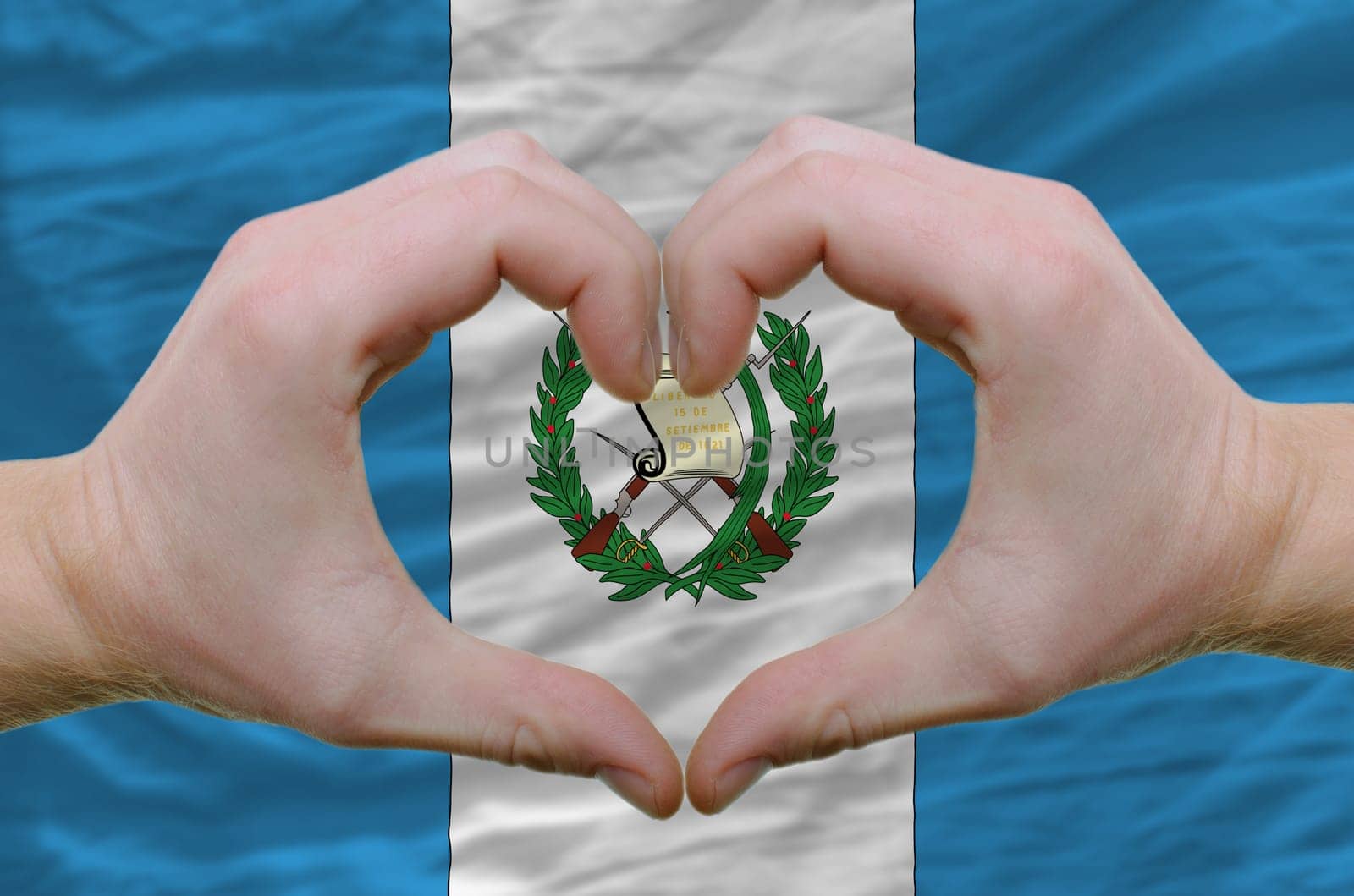 Gesture made by hands showing symbol of heart and love over guatemala flag