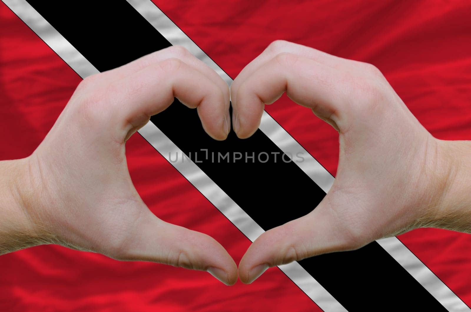 Gesture made by hands showing symbol of heart and love over trinidad and tobaog flag