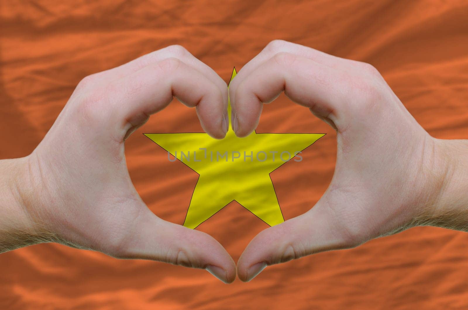 Gesture made by hands showing symbol of heart and love over vietnam flag
