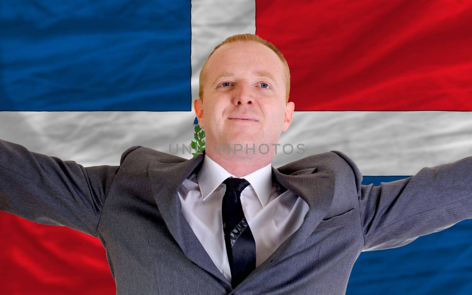 joyful investor spreading arms after good business investment in dominican republic, in front of flag