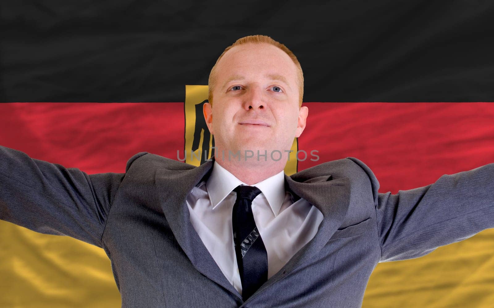 joyful investor spreading arms after good business investment in germany, in front of flag