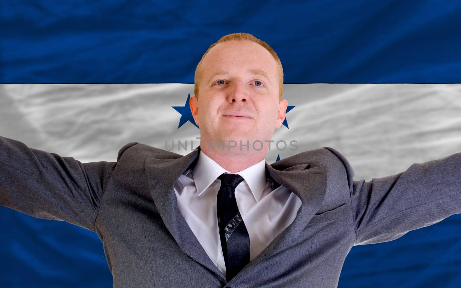 joyful investor spreading arms after good business investment in honduras, in front of flag