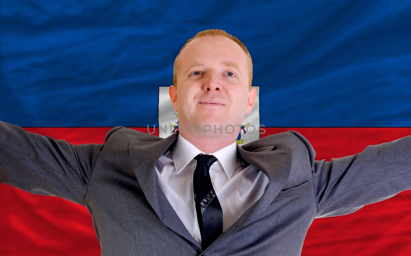joyful investor spreading arms after good business investment in haiti, in front of flag