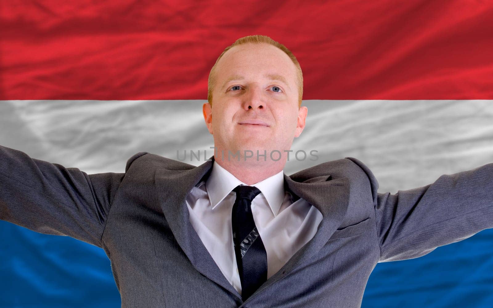 joyful investor spreading arms after good business investment in holland, in front of flag