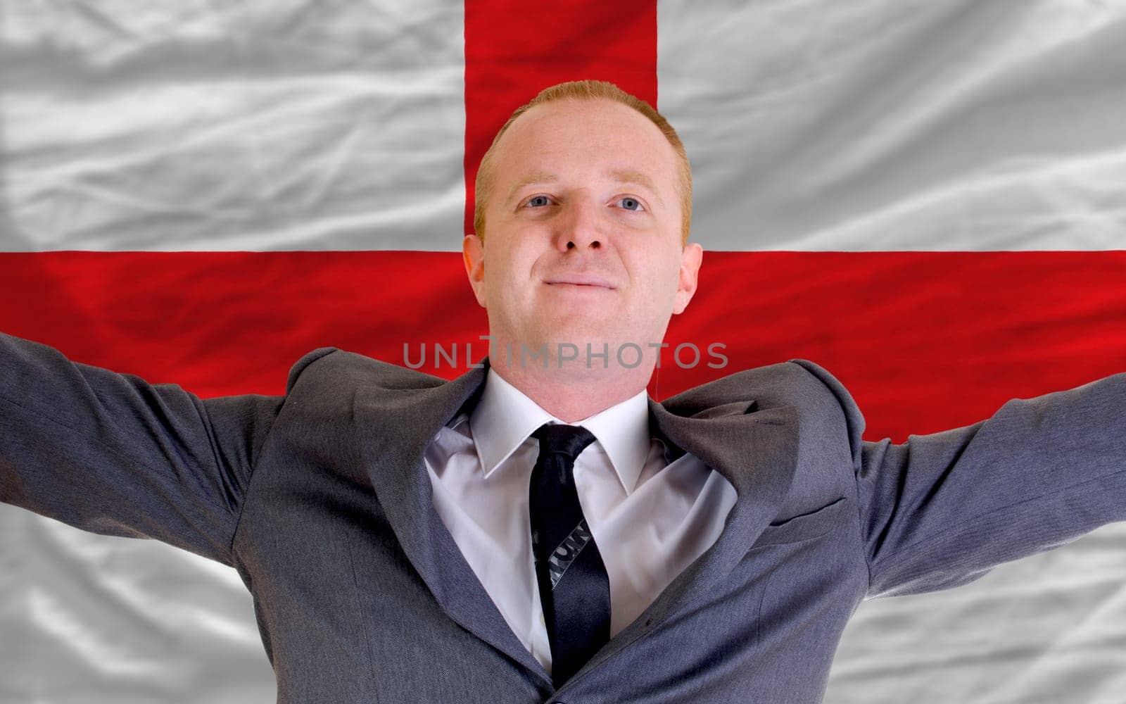 joyful investor spreading arms after good business investment in england, in front of flag