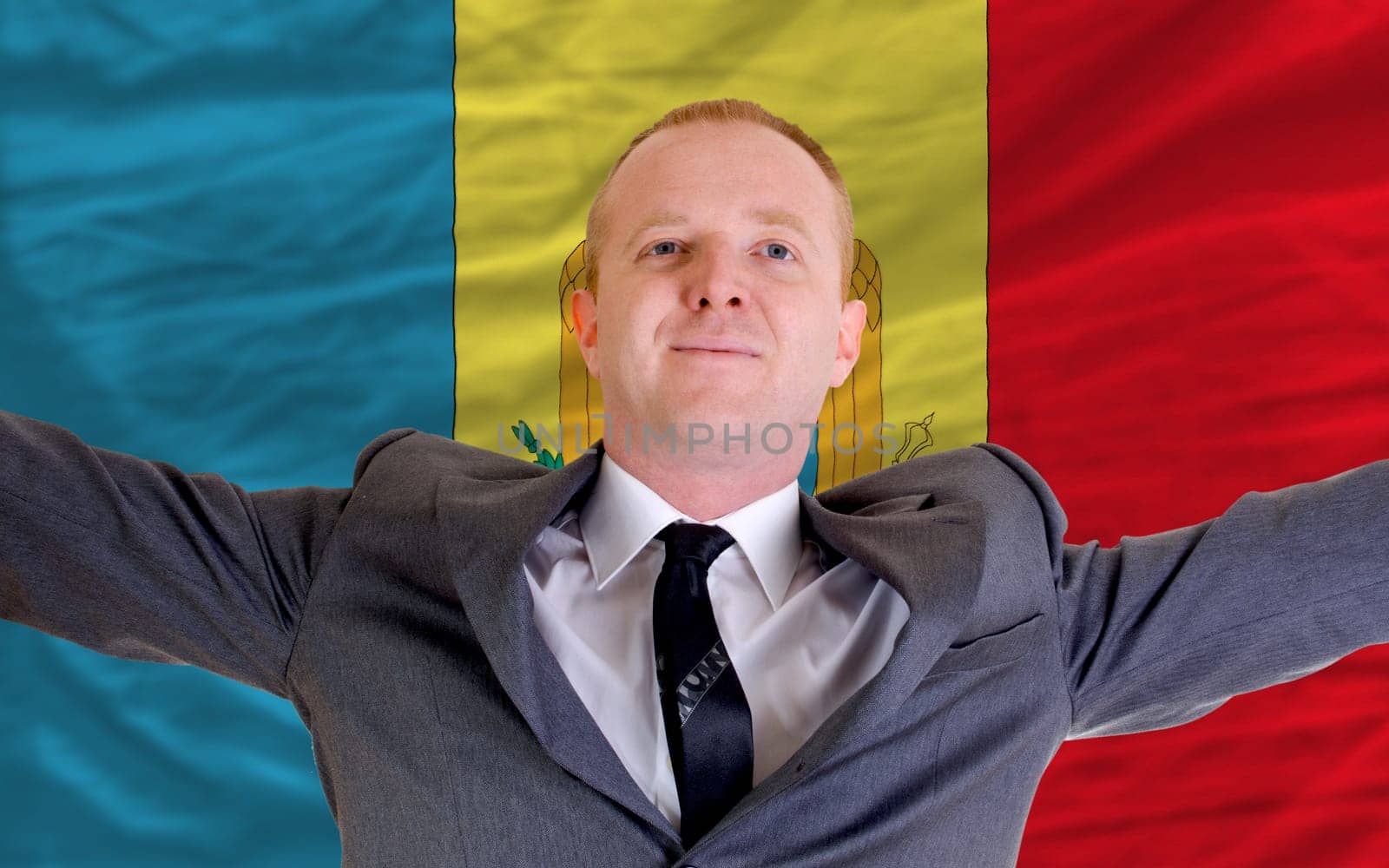 joyful investor spreading arms after good business investment in moldova, in front of flag