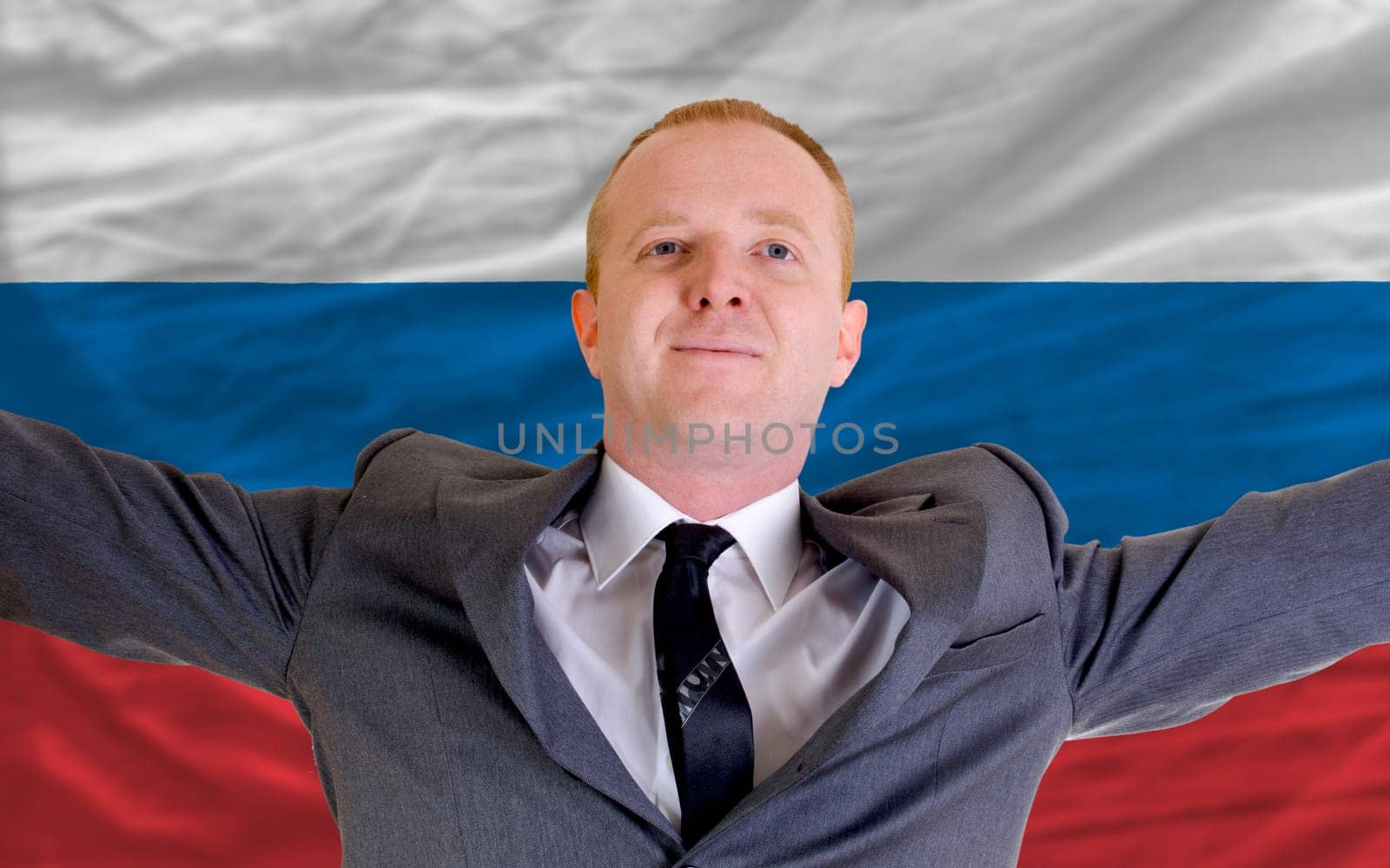 joyful investor spreading arms after good business investment in russia, in front of flag