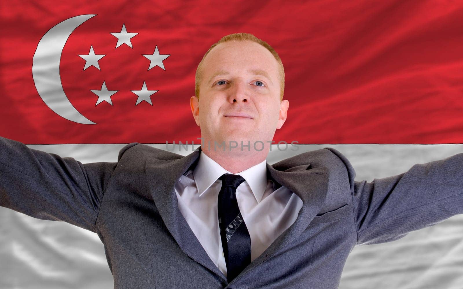 joyful investor spreading arms after good business investment in singapore, in front of flag