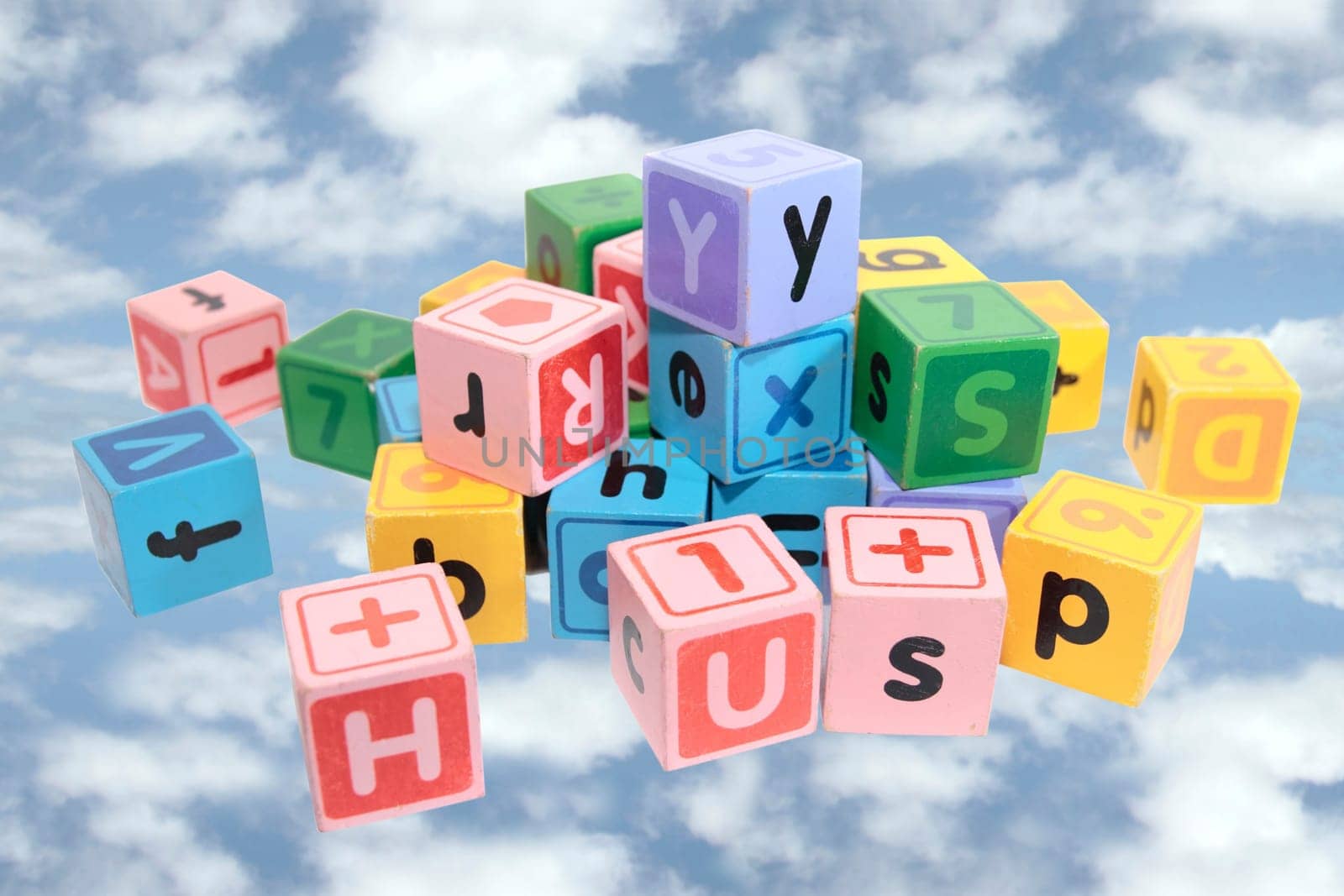 assorted childrens toy letter building blocks against a cloudy background with clipping path