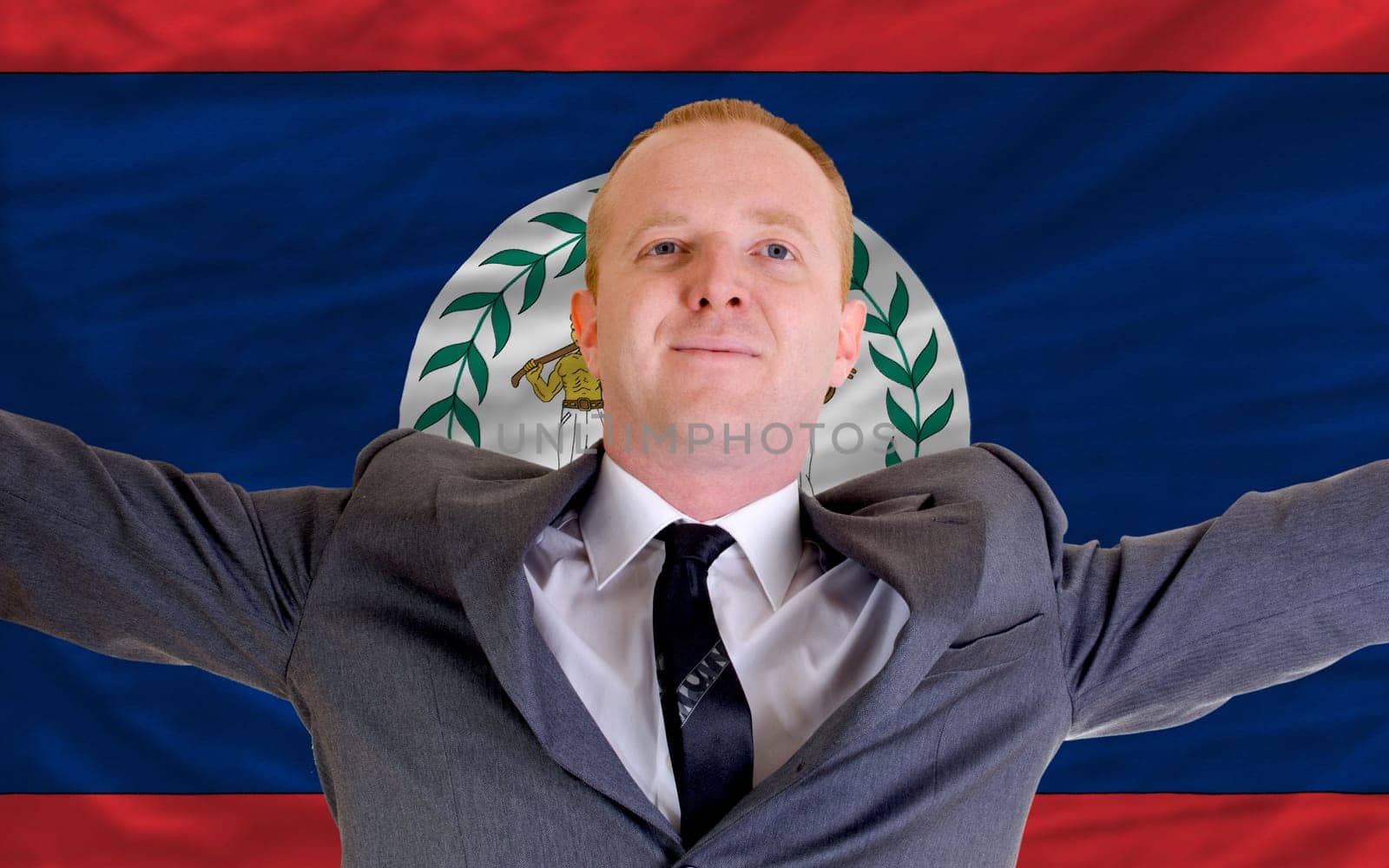 joyful investor spreading arms after good business investment in belize, in front of flag