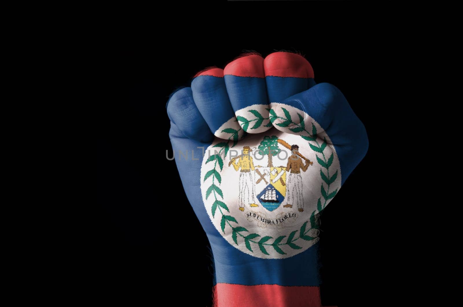 Low key picture of a fist painted in colors of belize flag