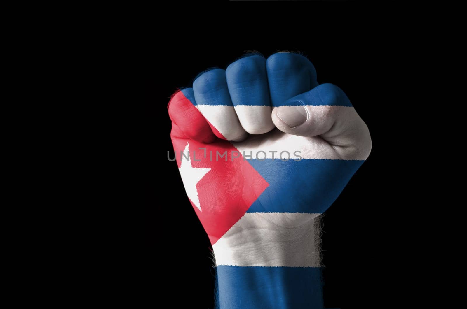 Low key picture of a fist painted in colors of cuba flag