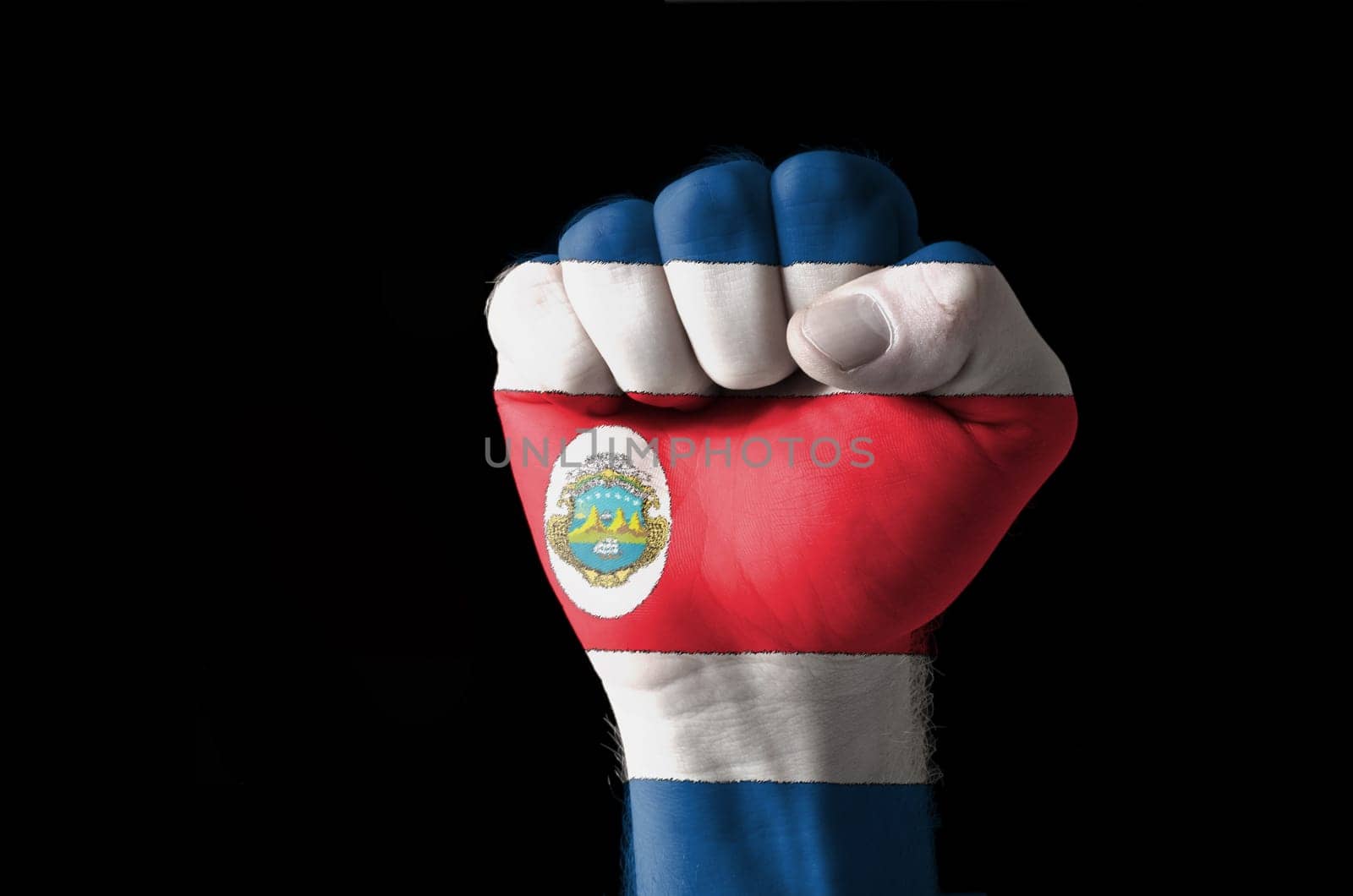 Low key picture of a fist painted in colors of costarica flag