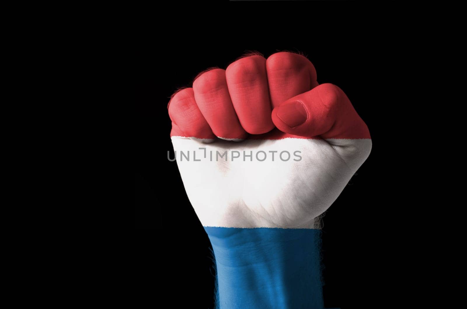 Low key picture of a fist painted in colors of netherlands flag