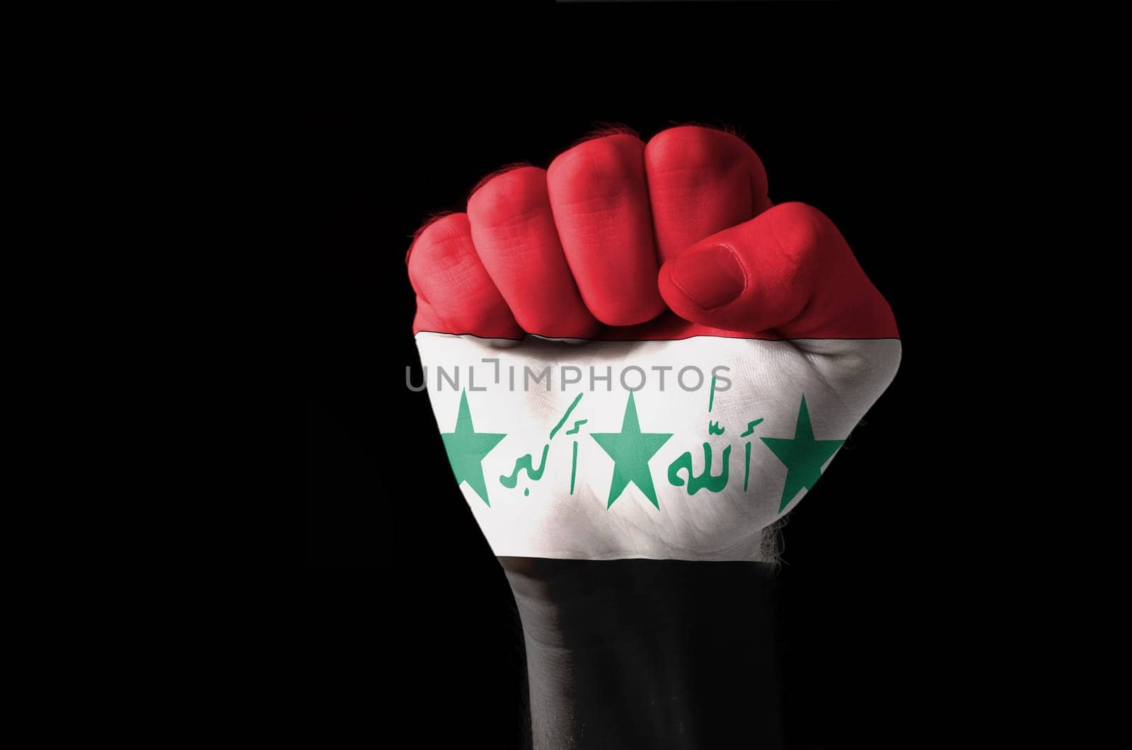 Low key picture of a fist painted in colors of iraq flag