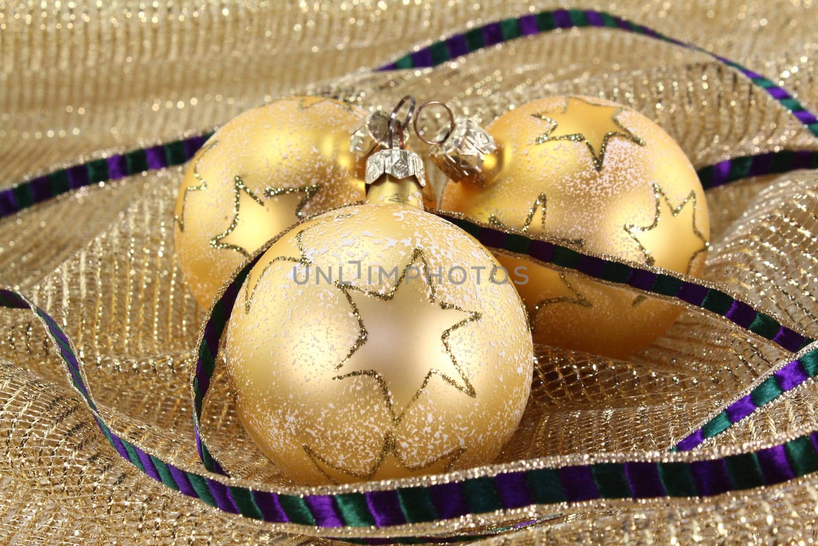 three Christmas tree baubles on golden decorative fabric