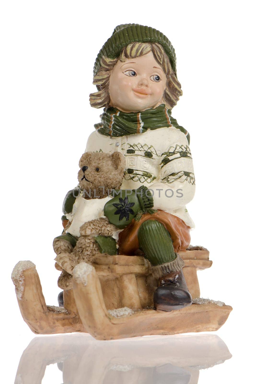 Miniature of child with bear dool on sleigh, on white reflective background.