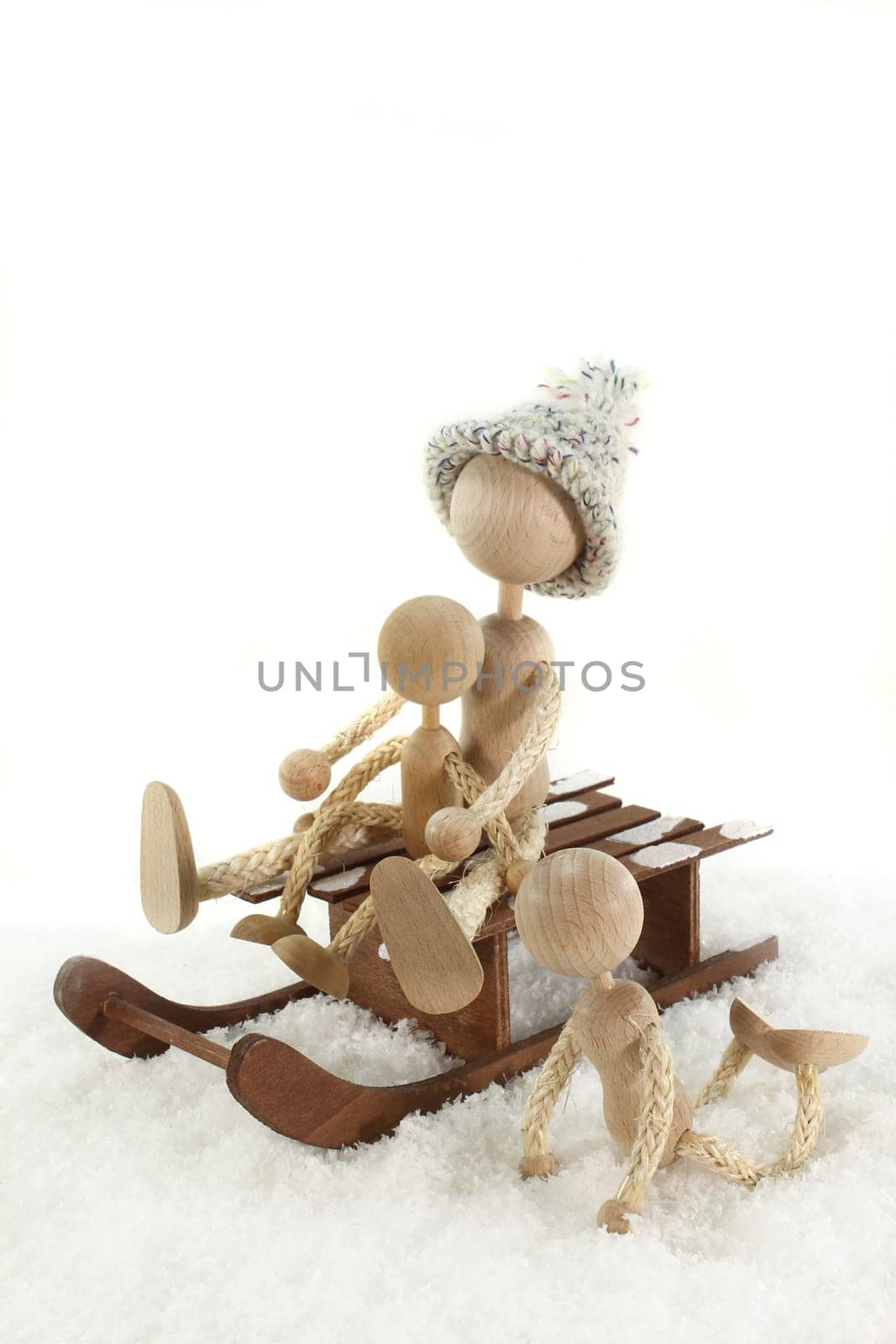 Wooden dolls sledding in the snow