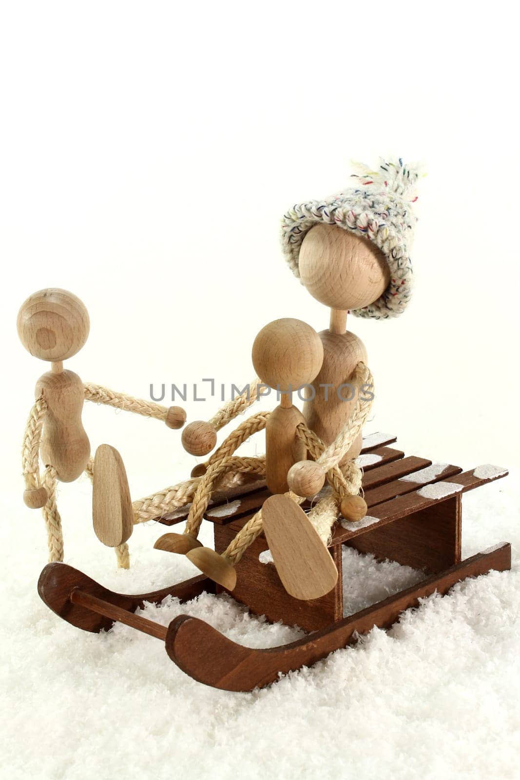 Wooden dolls sledding in the snow