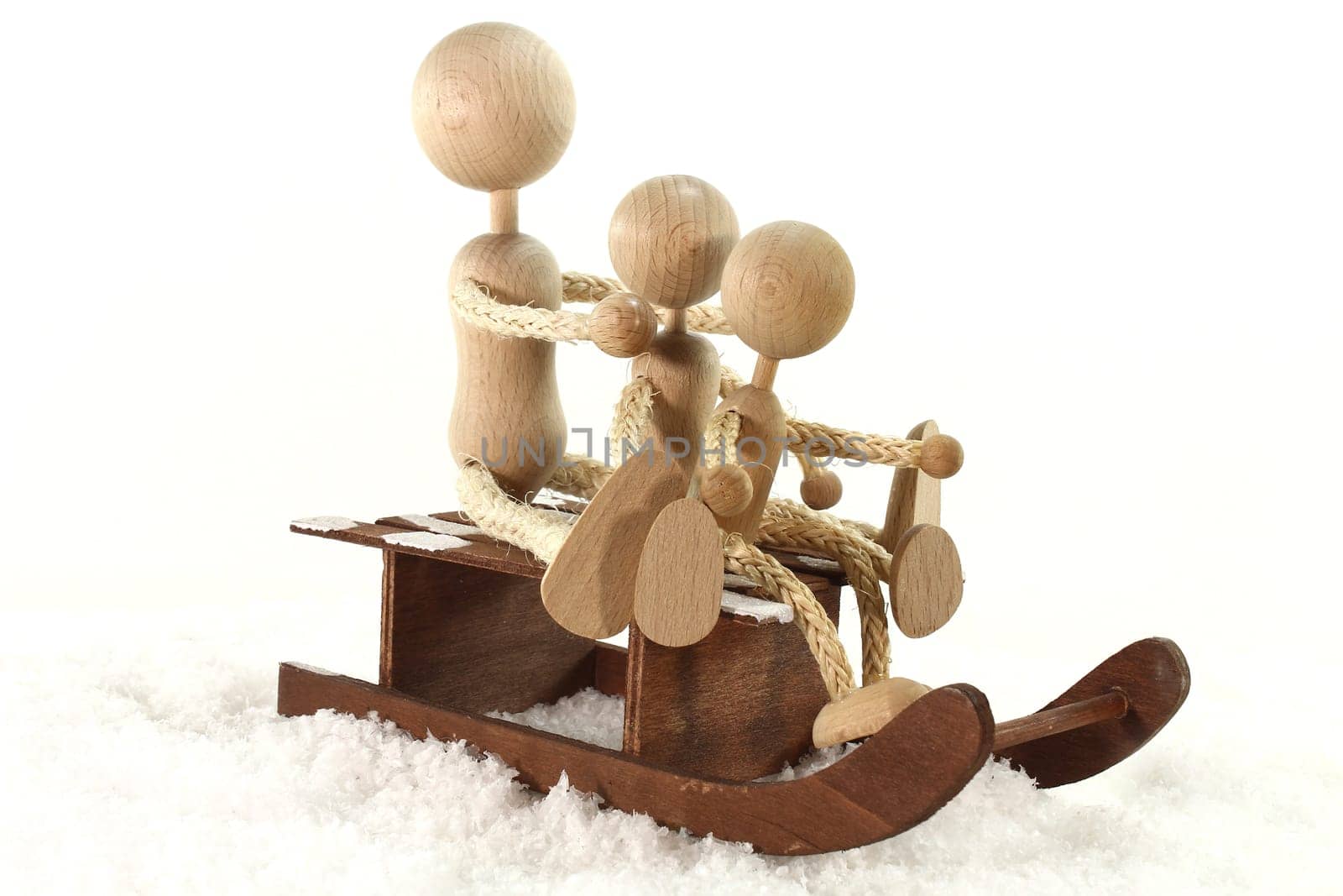 Wooden dolls sledding in the snow