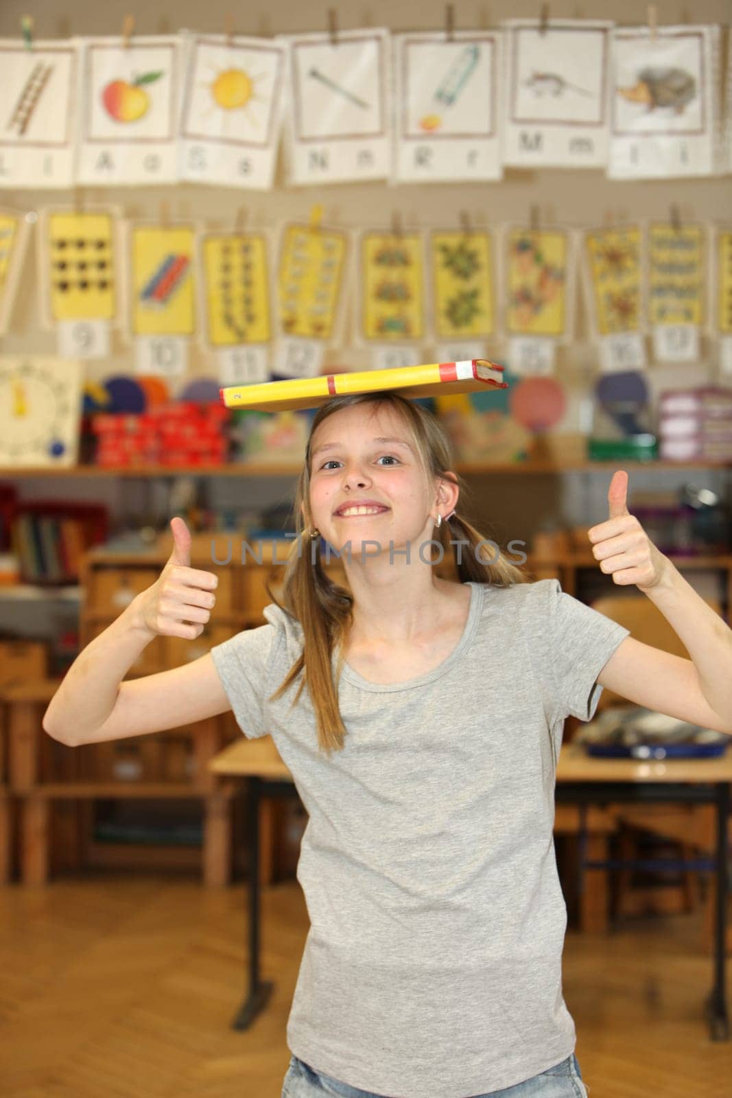 Hilarious girl at school shows thumb up. She has a textbook on the head.