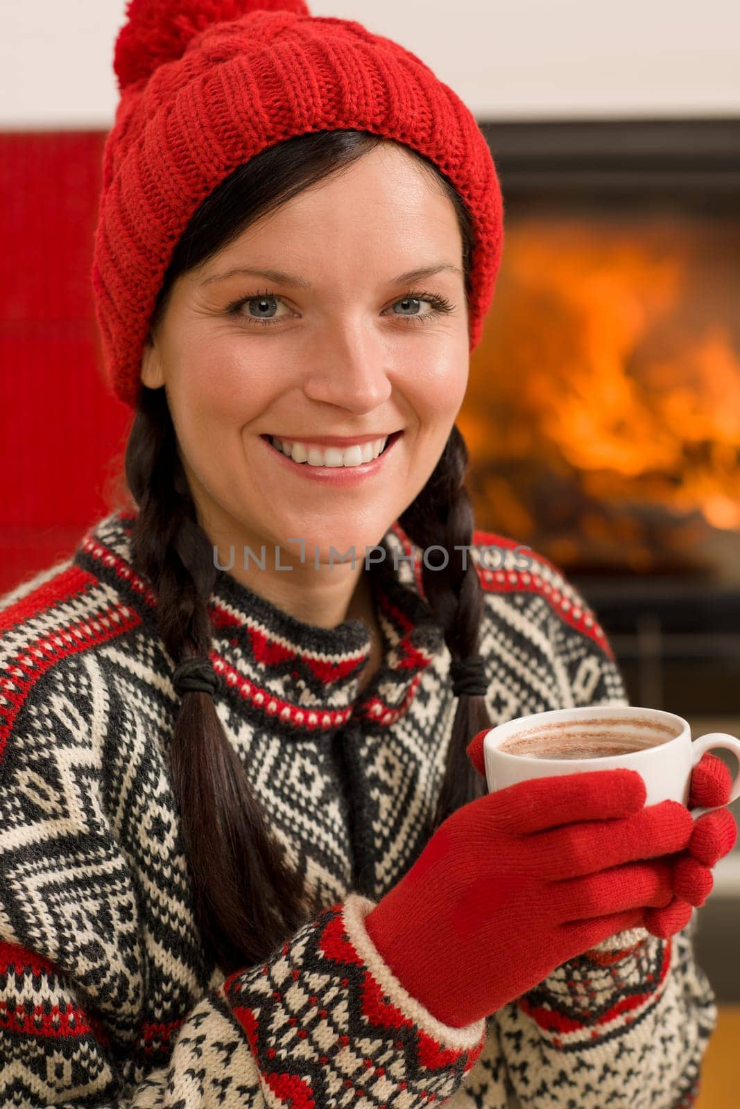 Winter christmas woman with hat and gloves drink by fireplace