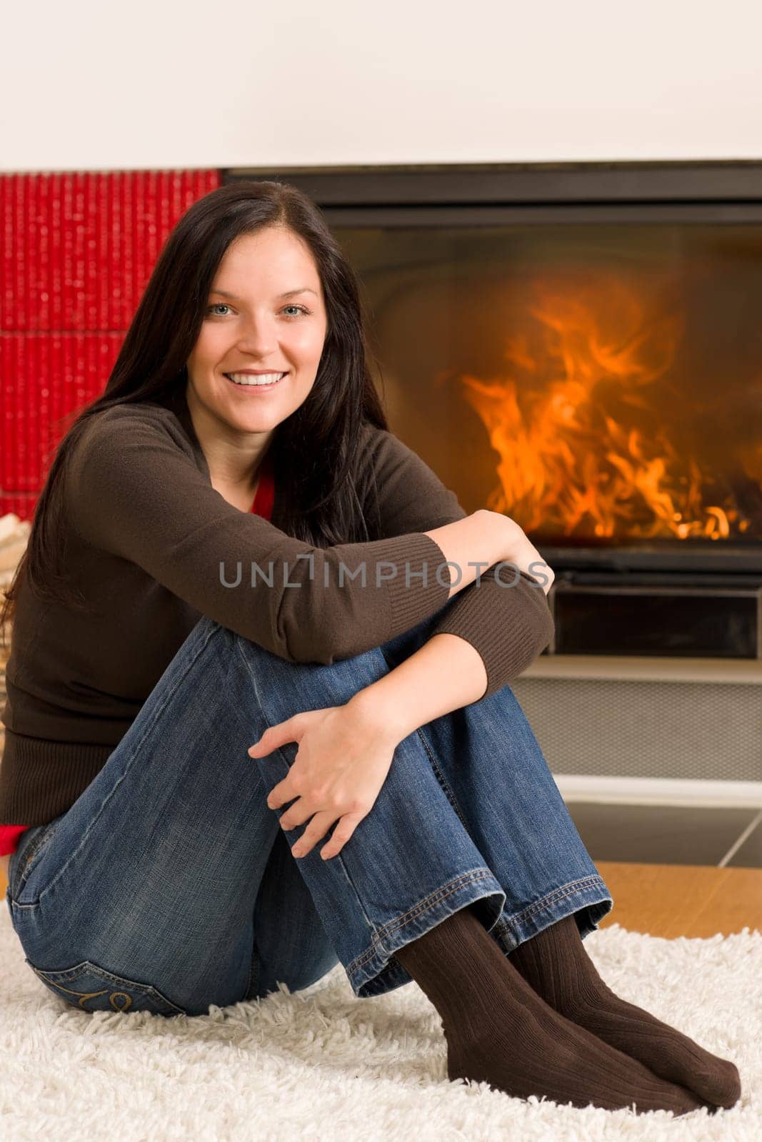 Beautiful happy young woman sitting front of home fireplace