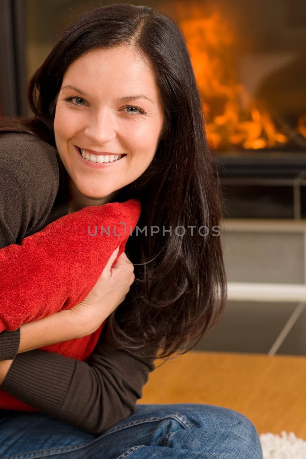 Beautiful happy young woman sitting front of home fireplace