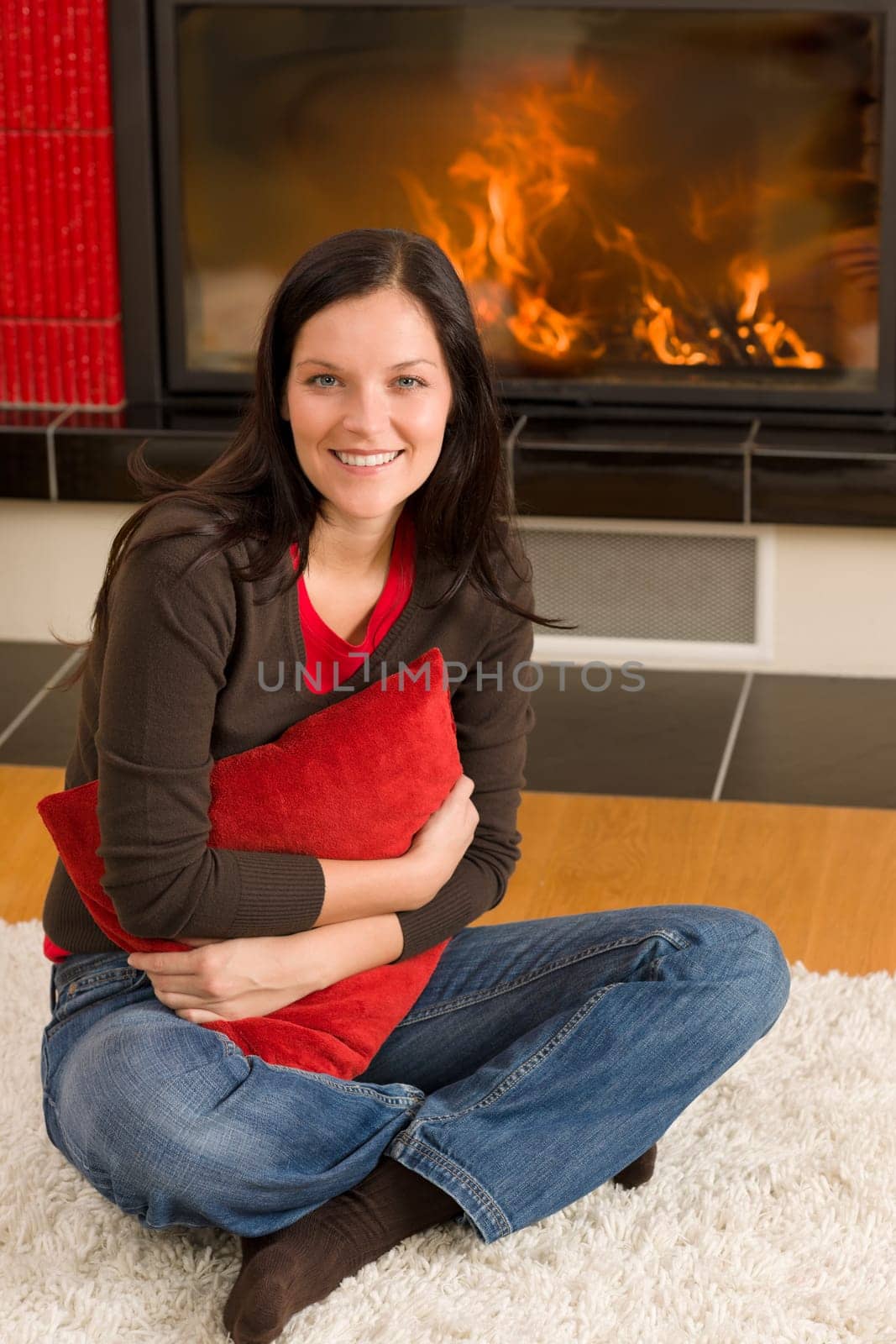 Beautiful happy young woman sitting front of home fireplace