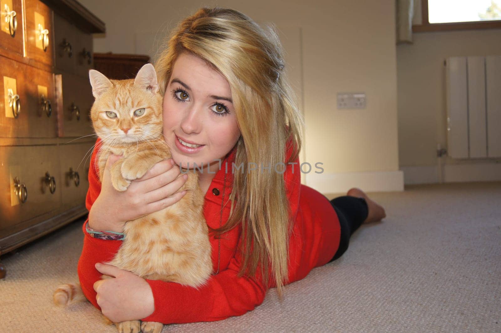 Girl laying on her bedroom floor cuddling her pet cat