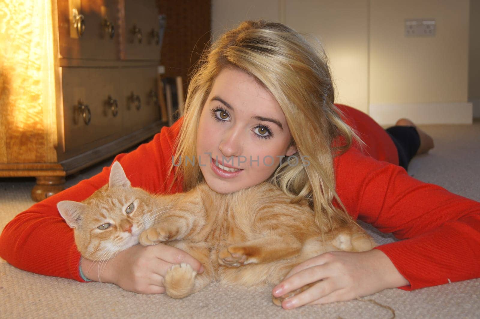 Girl laying on her bedroom floor cuddling her pet cat