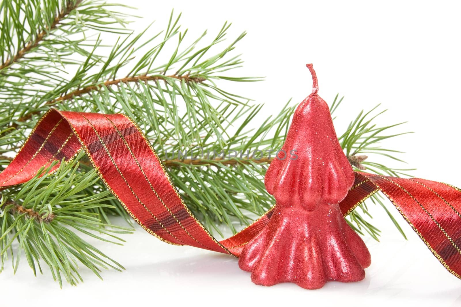 red christmas candle and pine branch over a white background