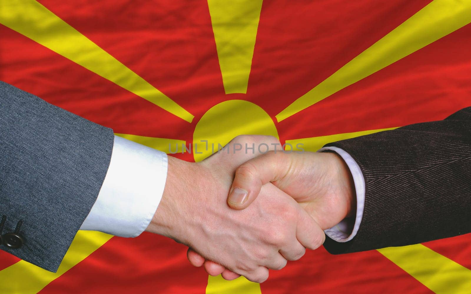 two businessmen shaking hands after good business investment  agreement in macedonia, in front of flag