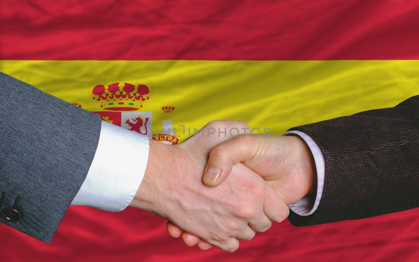 two businessmen shaking hands after good business investment  agreement in spain, in front of flag