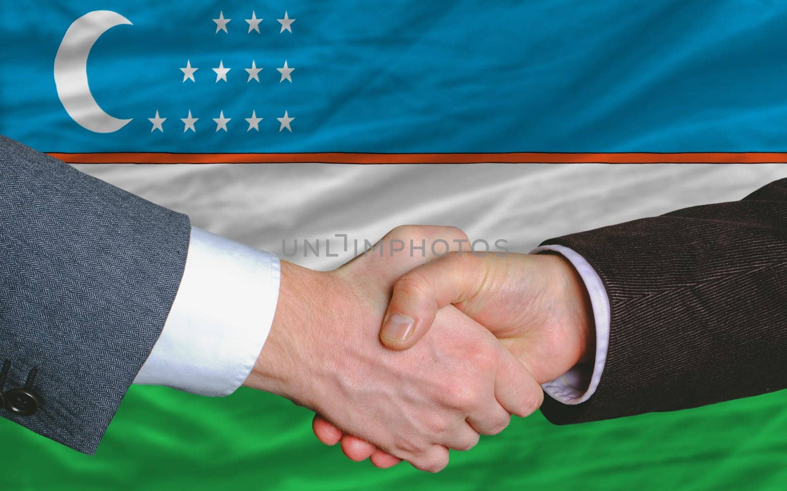 two businessmen shaking hands after good business investment  agreement in uzbekistan, in front of flag