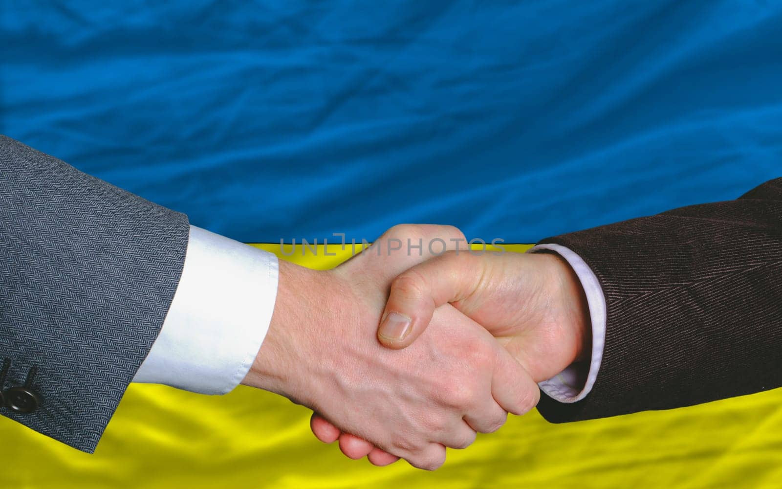 two businessmen shaking hands after good business investment  agreement in ukraine, in front of flag
