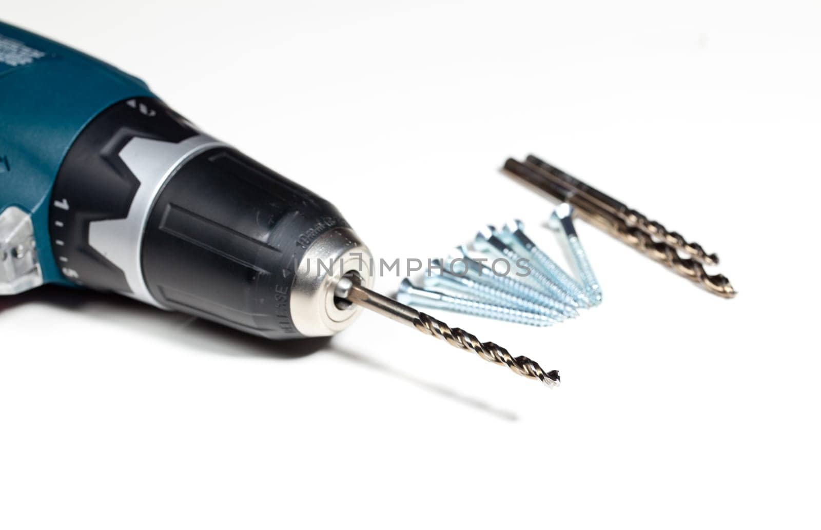 Drill bit in the chuck of power drill with wood screws on table