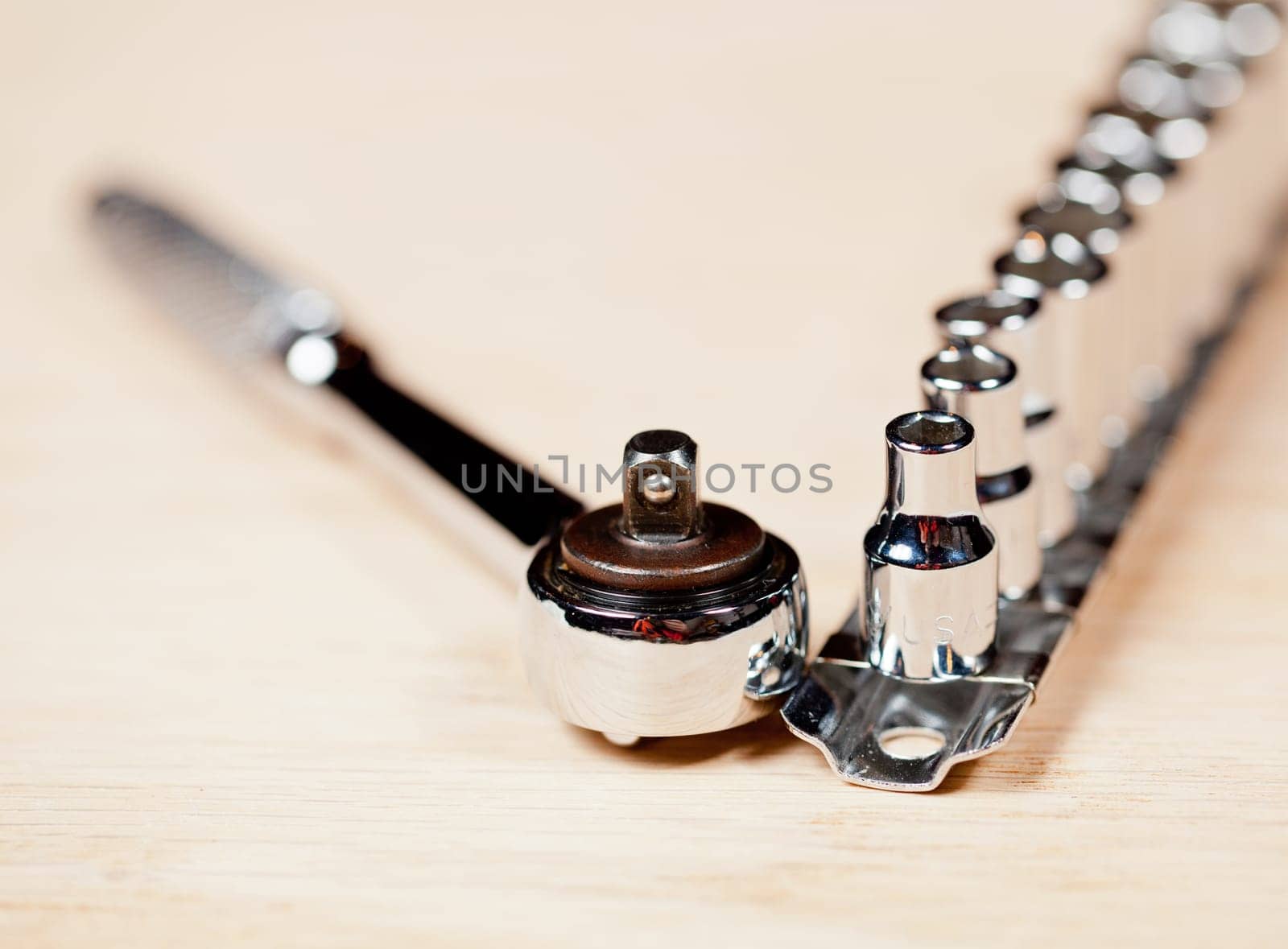 Wrench and miniature sockets in a holder on a piece of wood bench