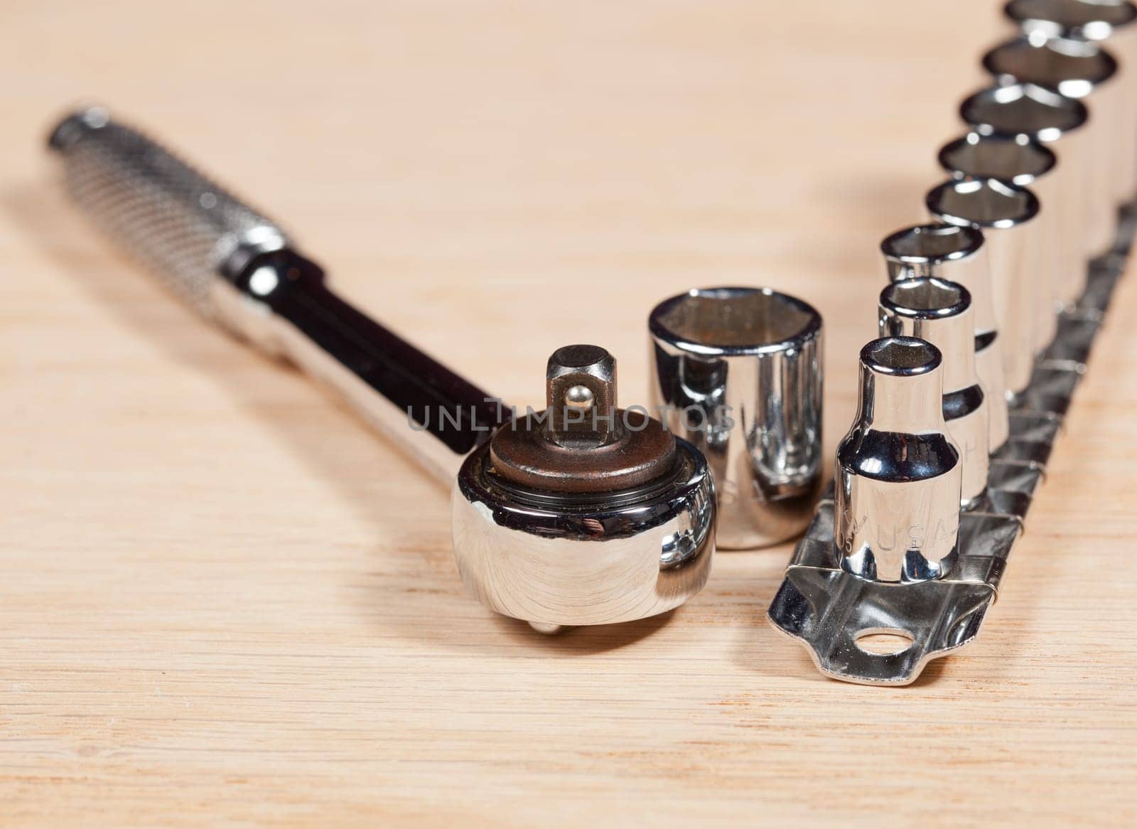 Wrench and miniature sockets in a holder on a piece of wood bench