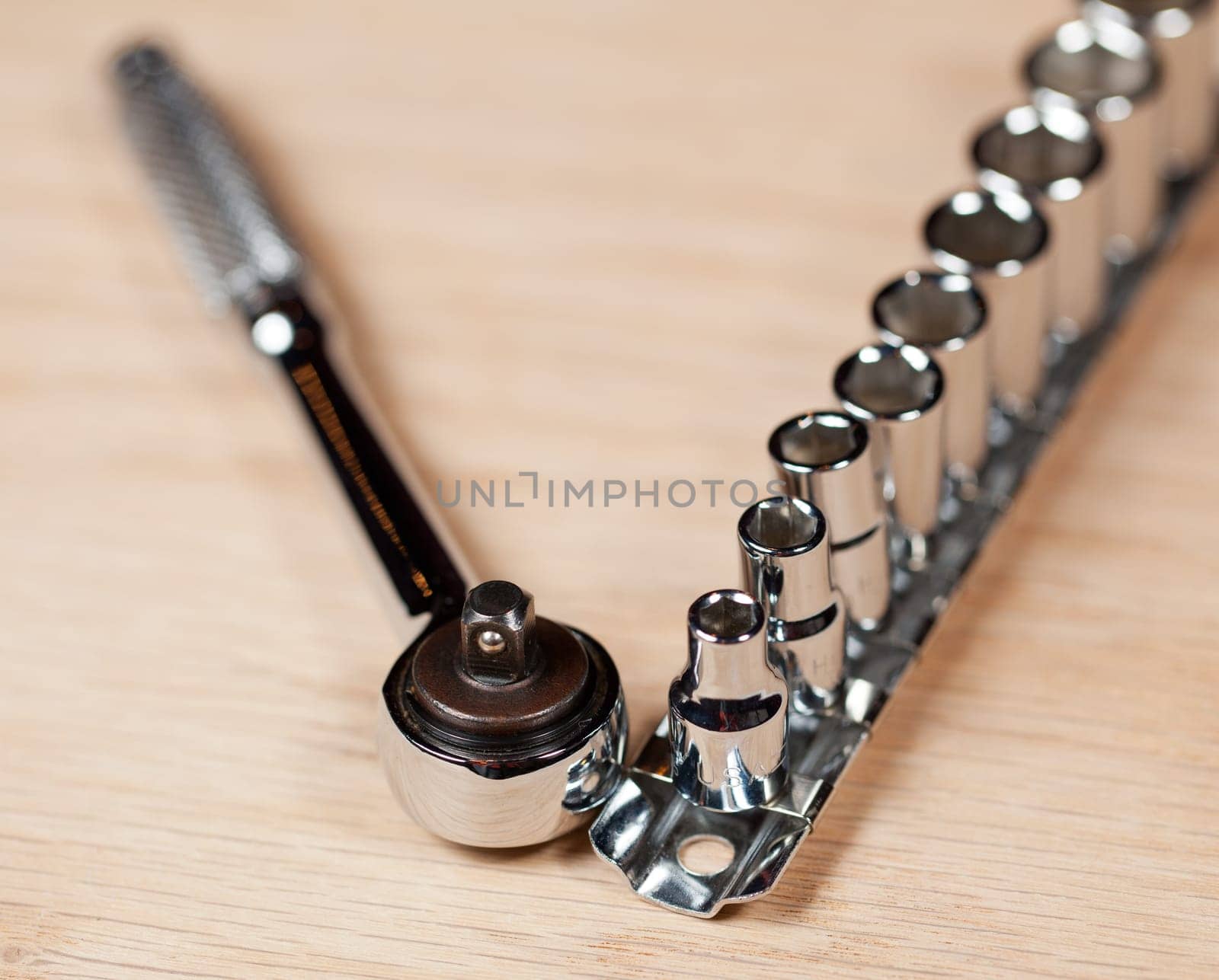 Wrench and miniature sockets in a holder on a piece of wood bench