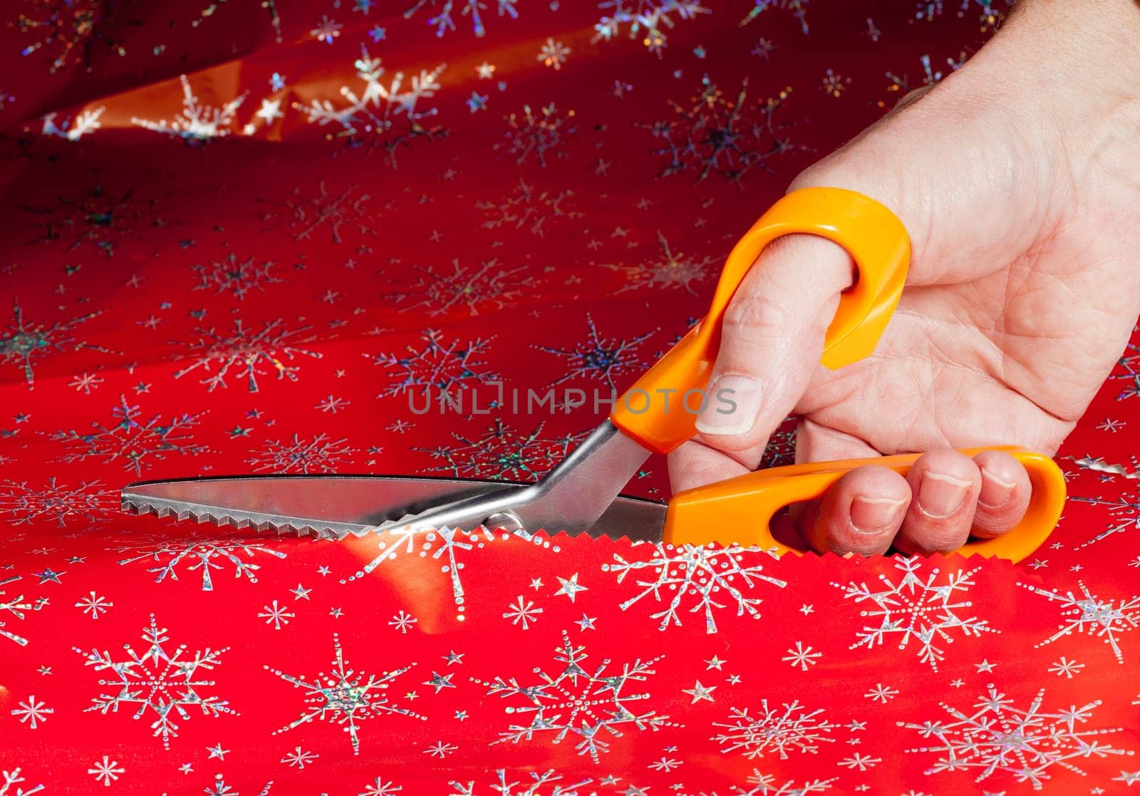 Christmas paper being cut by special scissors to create pattern in the cut edge