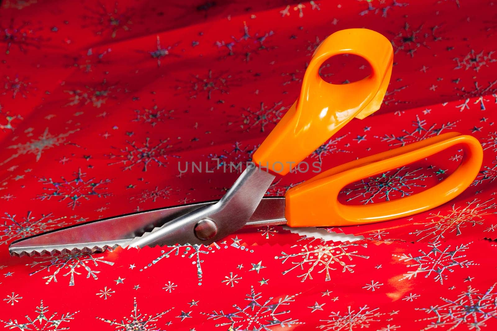 Christmas paper being cut by special scissors to create pattern in the cut edge