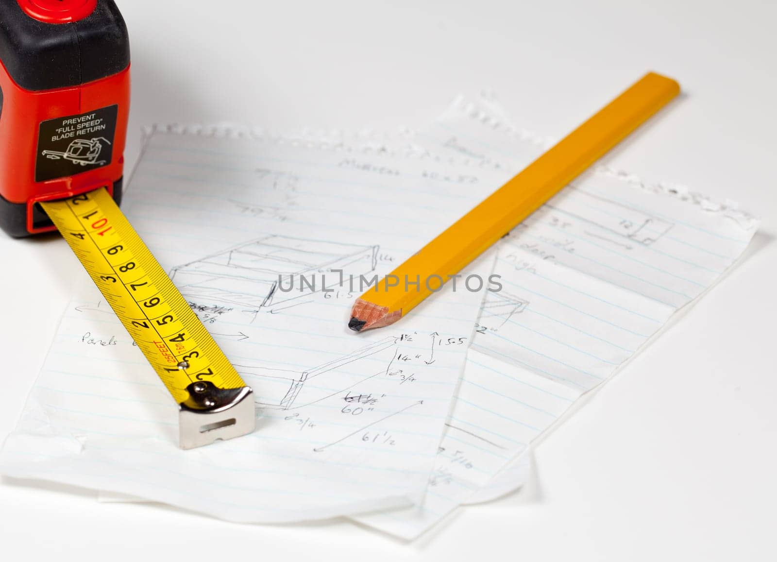 Tape measure and pencil laying on plans for a woodworking project