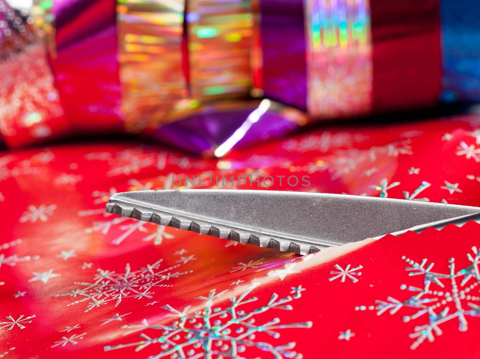 Christmas paper being cut by special scissors to create pattern in the cut edge
