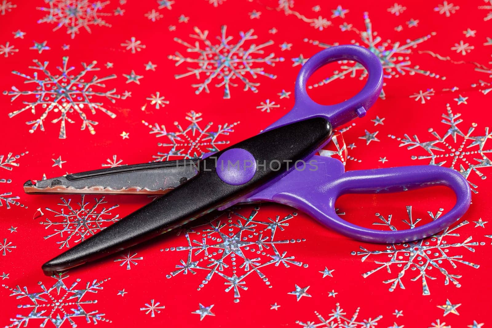 Christmas paper being cut by special scissors to create pattern in the cut edge