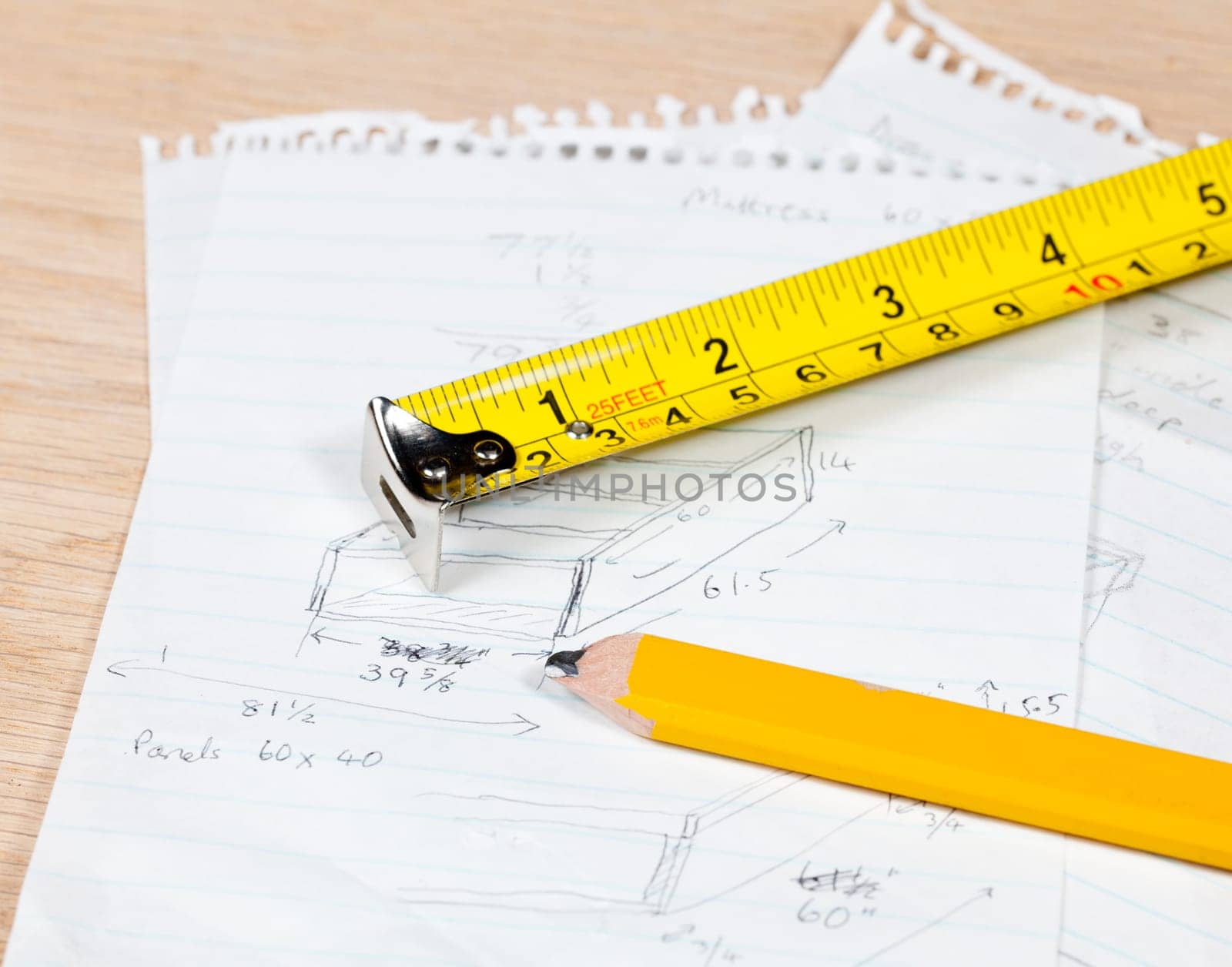 Tape measure and pencil laying on plans for a woodworking project