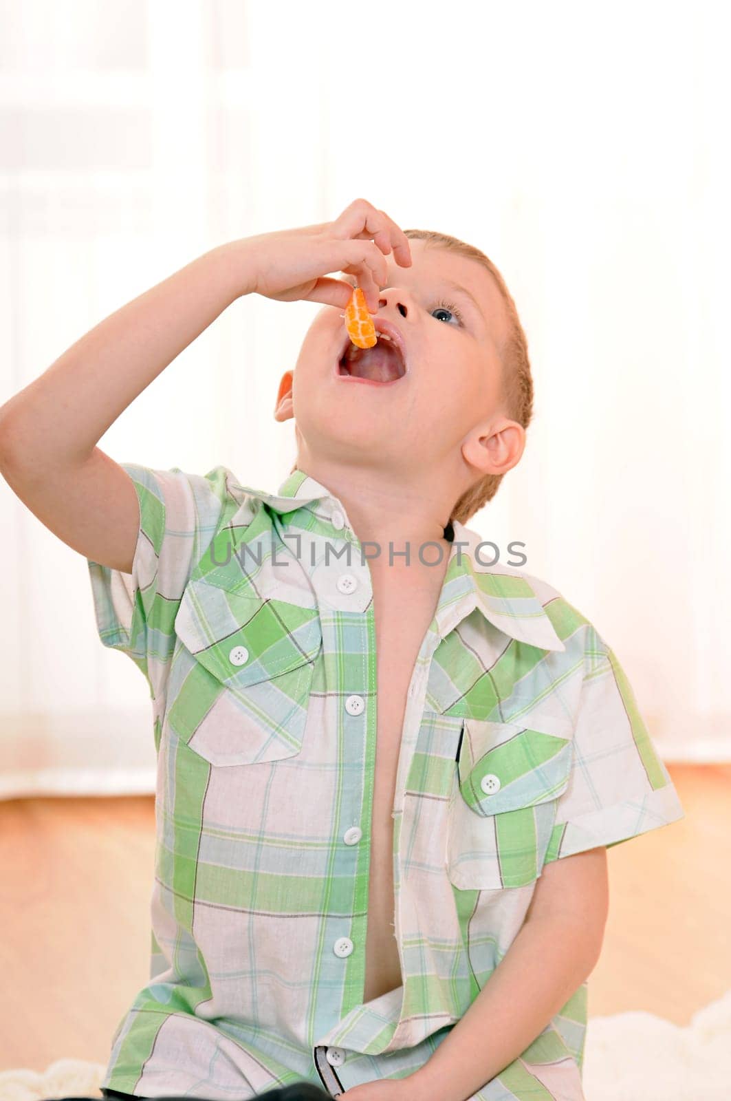 child sitting on the floor and eats an orange