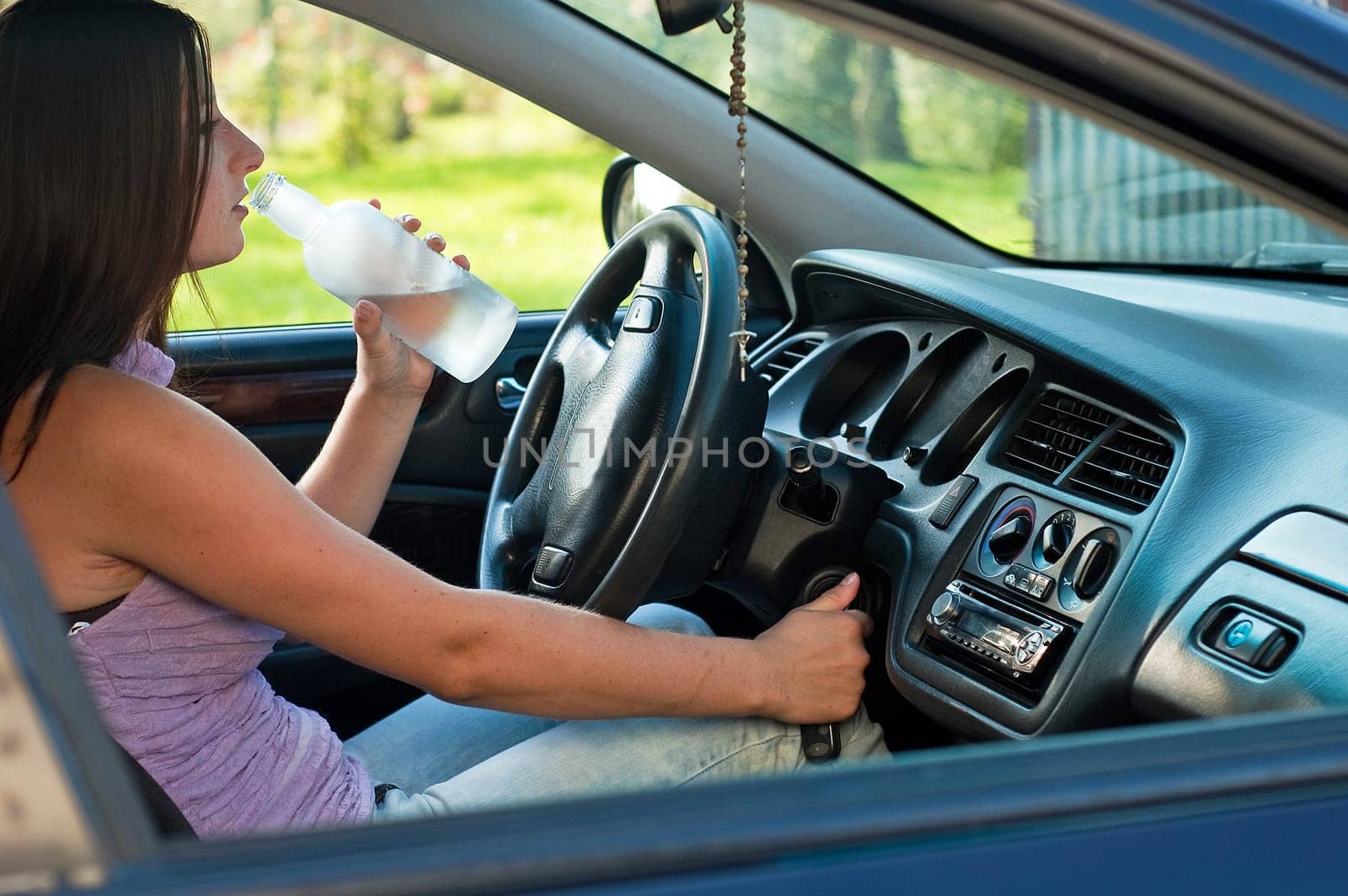 woman drinking alcohol during a drive in a car