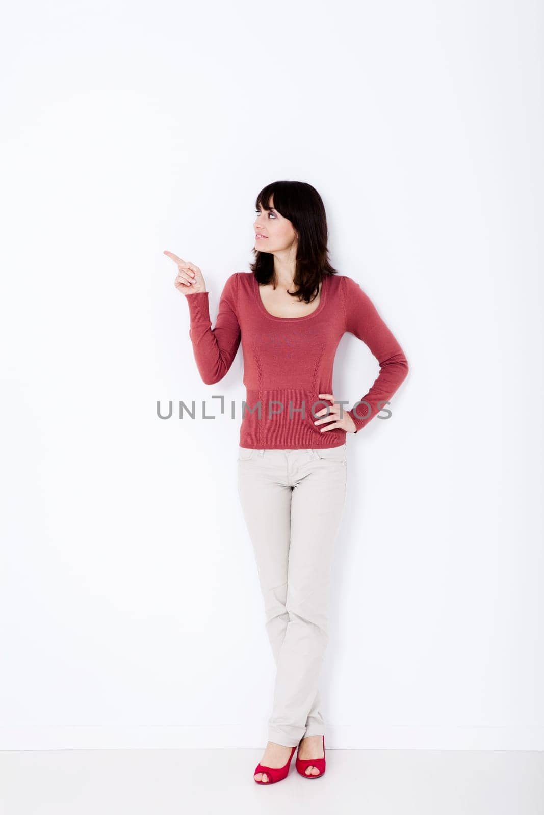 Beautiful woman standing and pointing up. Studio shot.
