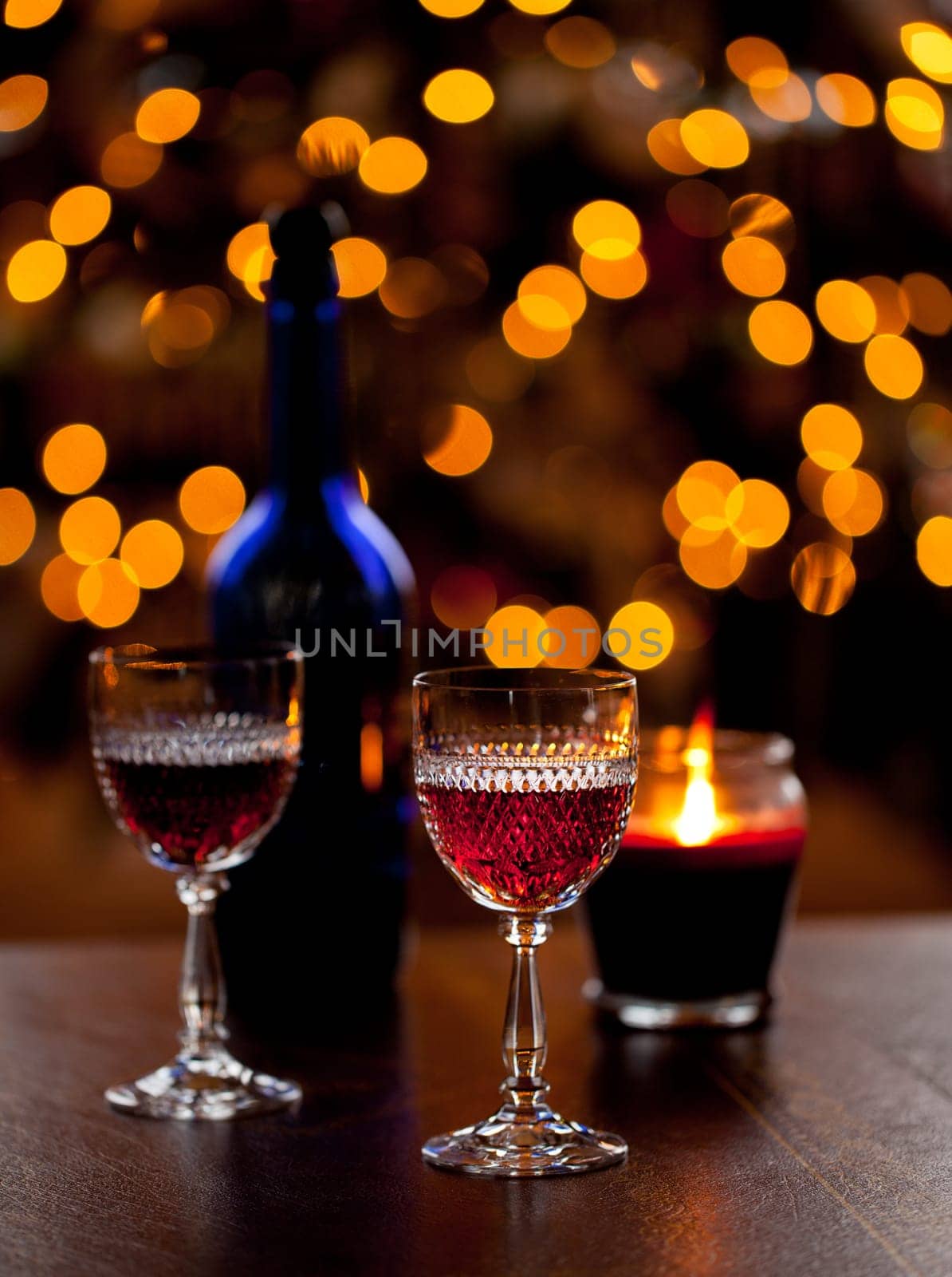 Cut glass sherry or port glasses in front of an out of focus christmas tree with blue bottle